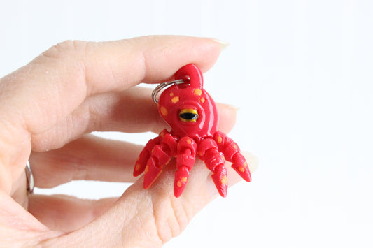 Close-up of the 3D-printed octopus with curled tentacles keychain showing its face, markings, and textured surface.
