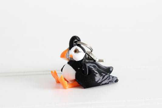 3D-printed black, white, and orange puffin keychain with a silver swivel quick-clip on a white background.