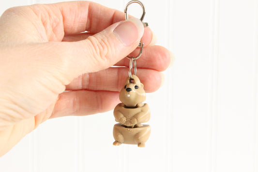 Hand holding the 3D-printed brown groundhog keychain to show its size, colors, and silver swivel clip.