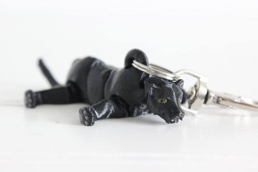 Articulated black panther keychain lying down with sculpted facial features and silver swivel quick-clip.