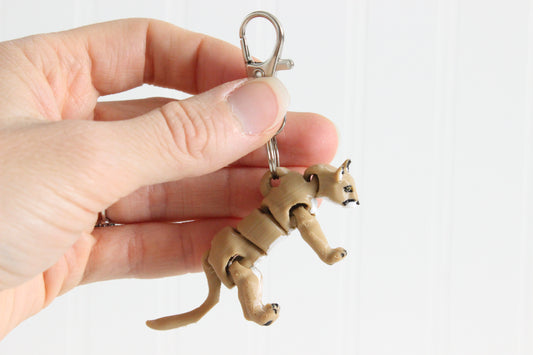 Hand holding the articulated cougar keychain for size reference.