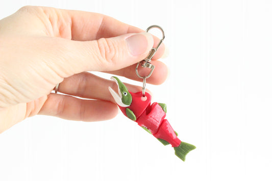 Hand holding a 3D printed sockeye salmon keychain with swivel quick-clip key ring, showing red body and green fin detail