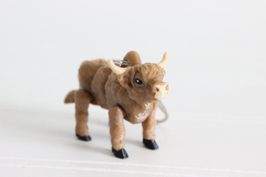 Close-up of the 3D-printed shaggy brown Highland cow keychain showing its face, markings, and textured surface.