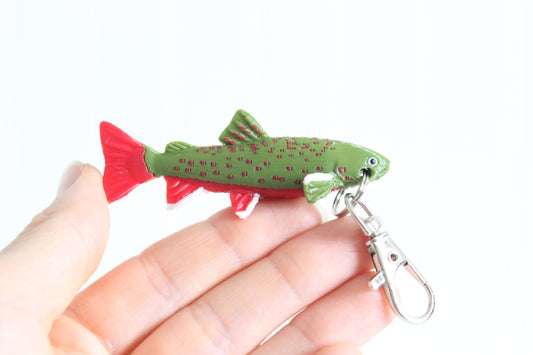 Hand holding the 3D-printed brook trout with spotted markings keychain to show its size, colors, and silver swivel clip.