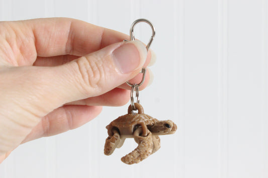 Side view of 3D printed brown sea turtle keychain held in a person's hand
