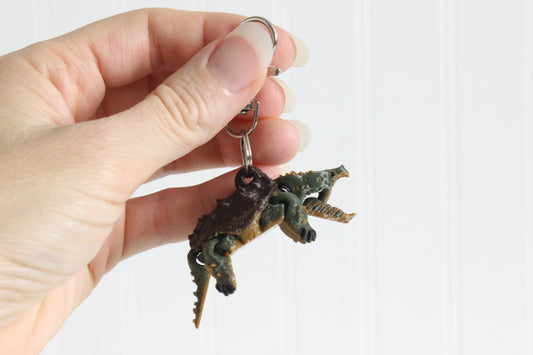 Hand holding a 3D printed alligator snapping turtle keychain showing open jaw and green textured body with swivel quick-clip key ring