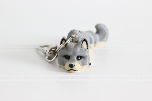 Alternate view of the 3D-printed gray wolf keychain showing its sculpted face and gold eyes.