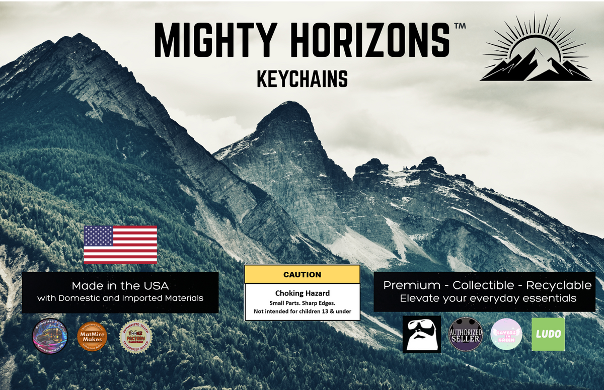 Mighty Horizons Keychains wilderness retail display sign with forested mountain peaks, U.S.-made materials statement, choking-hazard warning for ages 13 and under, premium collectible recyclable message, and designer attribution logos.